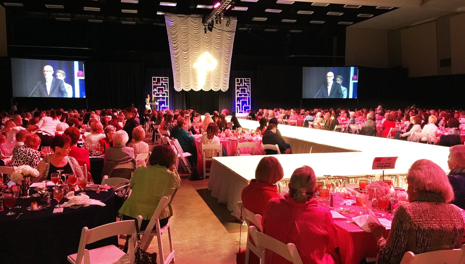 Large ballroom gala with stage lighting and screens